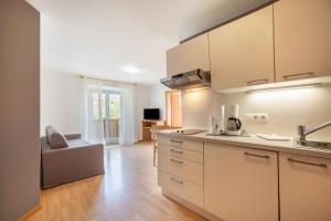 uma cozinha com armários brancos e uma sala de estar em Mosttragerhof Appartment 1 em Scena
