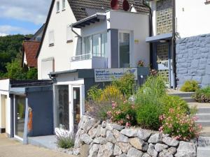 a white house with a stone wall in front of it at Ferienwohnung Kupfer in Niestetal