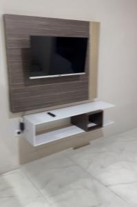a flat screen tv on a wall with a shelf at Adesha Guest House in Tondo