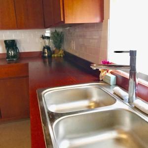 a kitchen with a stainless steel sink and wooden cabinets at VeLento Beach Level #9 in Caye Caulker