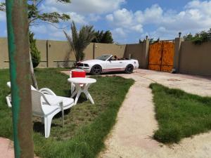 a white car parked in a yard with a table and chairs at Villa Mostafa Sadek, Swimming pool, Tennis & Squash - Borg ElArab Airport Alexandria in Borg El Arab