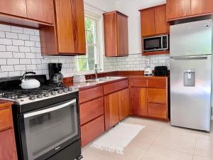 uma cozinha com armários de madeira e um frigorífico branco em VeLento Beach Level #9 em Caye Caulker
