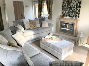een woonkamer met een bank en een open haard bij Oakwood Lodge in Morpeth