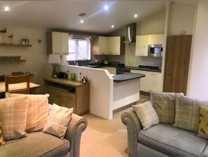een woonkamer met twee banken en een keuken bij Oakwood Lodge in Morpeth