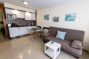 a living room with a couch and a table and a kitchen at Los Hibiscos 406 in Costa Calma