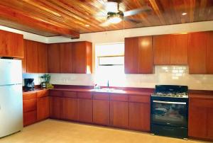 a kitchen with wooden cabinets and a white refrigerator at VeLento Partial Ocean View #8 in Caye Caulker