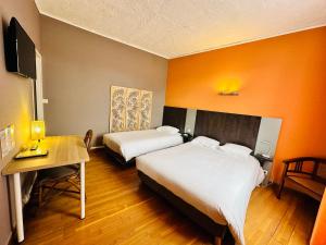 een hotelkamer met 2 bedden, een tafel en een bureau bij Hotel Italia in Tours
