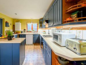 a large kitchen with blue cabinets and white appliances at 3 bed in Milford Haven 86881 in Milford Haven