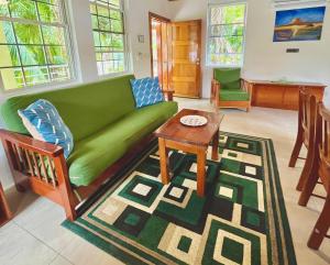 a living room with a green couch and a table at Caribbean Sunrise Villa in Caye Caulker