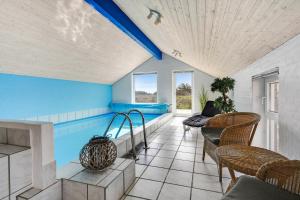 una piscina en una habitación con sillas y mesa en Holiday home with spa and pool by the sea - SJ670 en Harboør