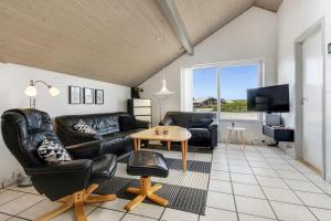 uma sala de estar com duas cadeiras de couro e uma mesa em Holiday home with spa and pool by the sea - SJ670 em Harboør