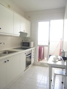 cocina con armarios blancos, mesa y ventana en Residencial Los Ibicencos V.v., en La Manga del Mar Menor