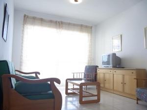 sala de estar con silla y TV en Residencial Los Ibicencos V.v., en La Manga del Mar Menor