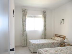 1 dormitorio con 2 camas y ventana en Residencial Los Ibicencos V.v., en La Manga del Mar Menor