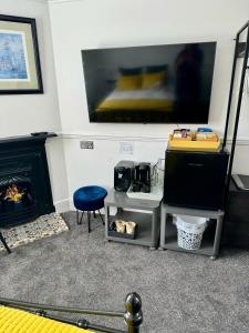 a living room with a tv and a chair and a fireplace at Pierremont En-Suite Rooms in Broadstairs