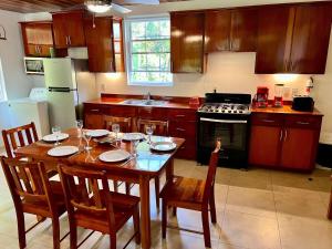 eine Küche mit einem Holztisch und Stühlen sowie eine Küche mit einem Herd in der Unterkunft Caribbean Sunrise Cottage in Caye Caulker