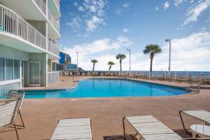 a resort swimming pool with chairs and the ocean at Tradewinds 001 by Vacation Homes Collection in Orange Beach
