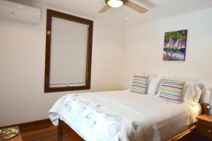 a white bedroom with a bed and a window at Hidden Gem Cabana in Caye Caulker