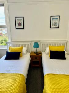 two beds with yellow pillows in a room at Pierremont En-Suite Rooms in Broadstairs