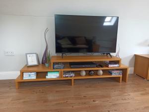 a flat screen tv on a wooden entertainment center at Little Wisteria in Canterbury