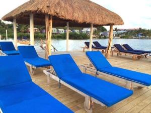 a group of blue lounge chairs and a straw umbrella at Sea Garden Cottage in Caye Caulker