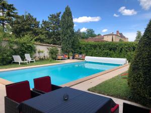 a swimming pool with chairs and a table in a yard at Les Loges de Bacchus in Chonas-lʼAmballan