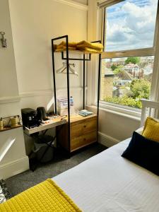 um quarto com uma cama, uma secretária e uma janela em Pierremont En-Suite Rooms em Broadstairs