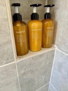 drei Flaschen Shampoo und Spülung auf einem Regal im Badezimmer in der Unterkunft Pierremont En-Suite Rooms in Broadstairs