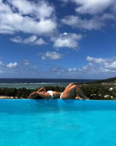 Le Marin, Rodrigues Island في Rodrigues Island: امرأة مستلقية على حافة حمام السباحة