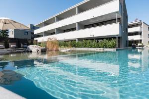 a swimming pool in front of a building at Relaxed Urban Living - Aparthotel und Boardinghouse in Dornbirn