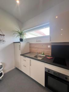 a kitchen with white cabinets and a sink and a window at gîte Lemarocha in Groffliers