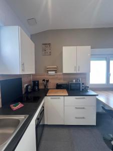 a kitchen with white cabinets and a sink at gîte Lemarocha in Groffliers