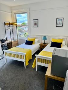 two beds in a room with a window and a tv at Pierremont En-Suite Rooms in Broadstairs