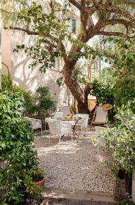 d'une terrasse avec une table et des chaises sous un arbre. dans l'établissement Hotel La Bienvenue, à La Croix-Valmer