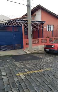 une voiture rouge garée devant un garage bleu dans l'établissement CasacentrocompartilhadaMogidasCruzes, à Mogi das Cruzes