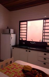 uma cozinha com uma grande janela, uma mesa e um frigorífico em CasacentrocompartilhadaMogidasCruzes em Mogi das Cruzes