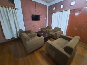 une salle d'attente avec des chaises, une table et une télévision dans l'établissement WISMA ACIDALIA SYARIAH, à Bandung