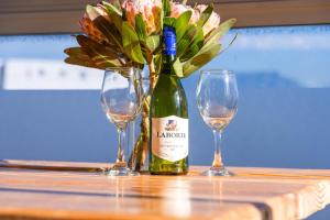 una bottiglia di vino e due bicchieri su un tavolo di Big Bay Beach Club 37 by HostAgents a Bloubergstrand