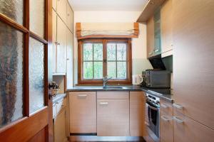 cocina con armarios de madera, fregadero y ventana en Ferienhaus Auszeithaus, 