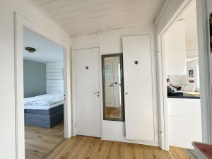 Cette chambre blanche comprend un lit et un miroir. dans l'établissement Lovely apartment with sea view on Hono, à Hönö