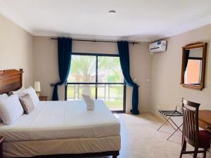 sypialnia z łóżkiem, biurkiem i oknem w obiekcie Seafront Residences & Hotel w mieście Bijilo