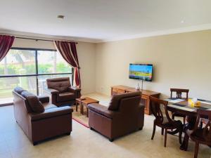 salon ze stołem, krzesłami i telewizorem w obiekcie Seafront Residences & Hotel w mieście Bijilo