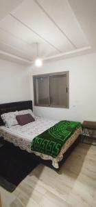 um quarto com uma cama com um cobertor verde em Kenitra em Kenitra