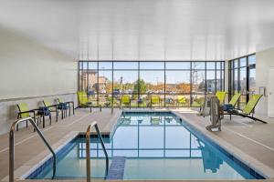 una piscina en un edificio con sillas y mesas en SpringHill Suites by Marriott Menomonee Falls, en Menomonee Falls