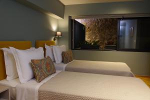 2 łóżka w pokoju hotelowym z oknem w obiekcie Absolute Athens Acropolis View w Atenach