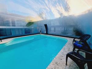 a swimming pool with two chairs next to at Posada del Angel- By HVH in Villa Carlos Paz