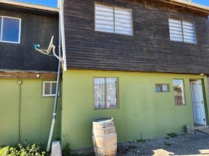 a green house with a barrel in front of it at Cabaña 6 personas Pichilemu excelente ubicación in Pichilemu
