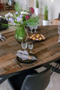 een houten tafel met een vaas van bloemen en glazen bij Huswell - Apartment with lake view & common indoor pool in Knokke-Heist