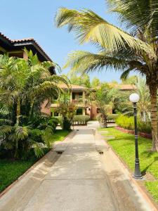 a walkway in front of a house with palm trees at Seafront Residences & Hotel in Bijilo