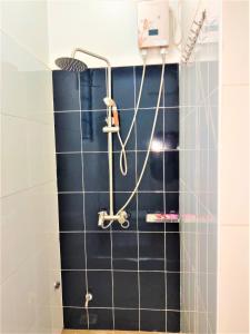 prysznic w łazience wyłożonej czarnymi kafelkami w obiekcie Ryker's Place w mieście Kampala